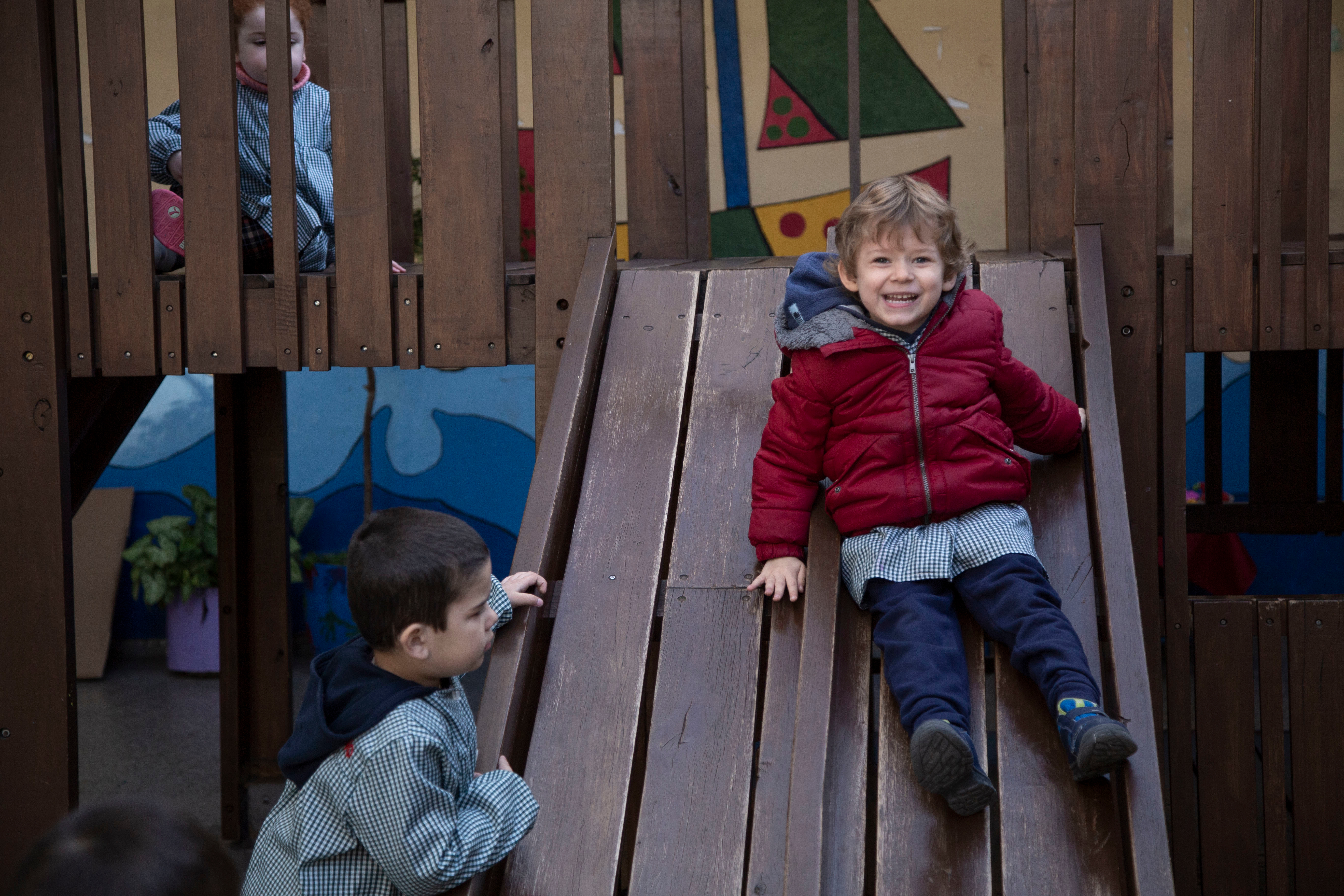 niño sonriendo mientras baja por un tobogán en el patio de su centro educativo