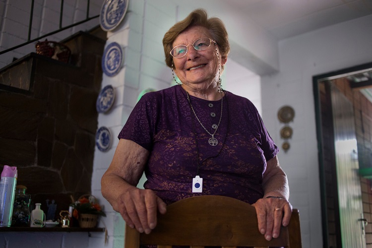Ángelica, usuaria de teleasistencia en casa, parada en el comedor de su casa agarrando una silla.