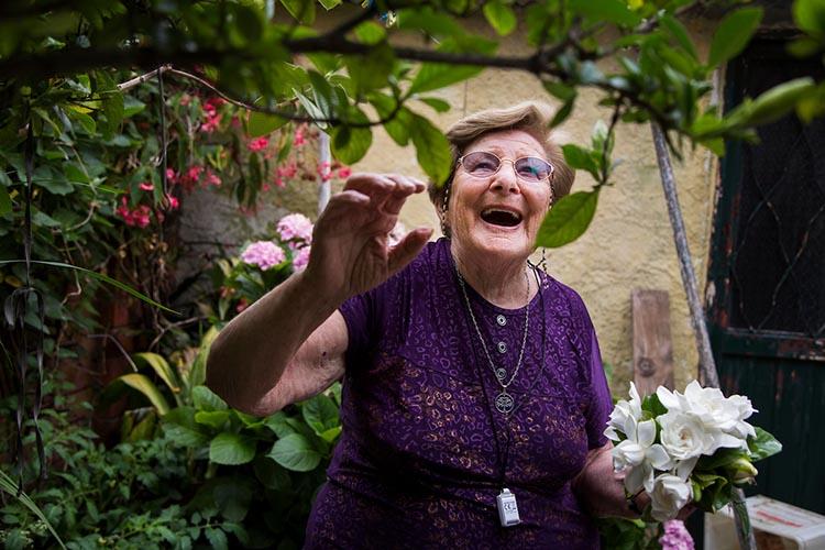 Usuaria de teleasistencia en casa agarrando jazmines en su jardín