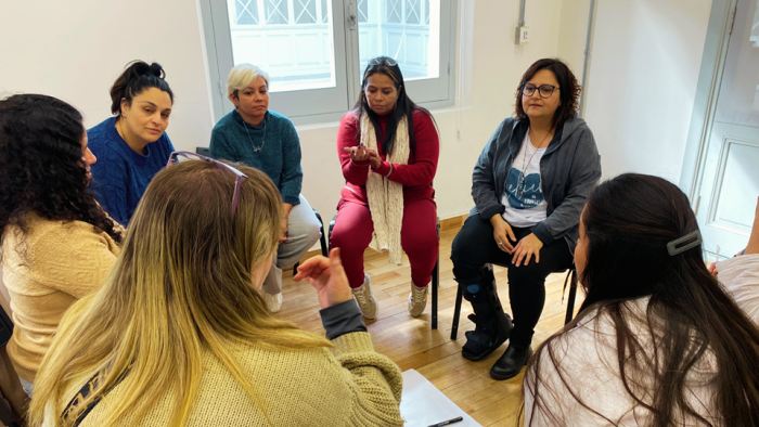 Imagen de 7 mujeres sentadas en círculo, conversando.