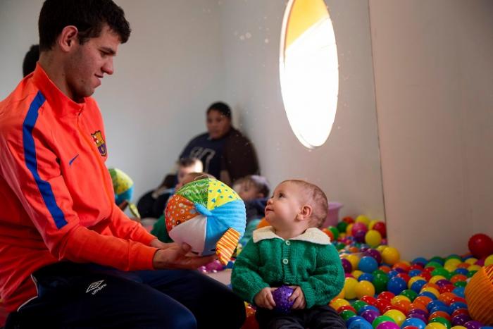 Un padre juega con su hijo pequeño con una pelota en CAIF