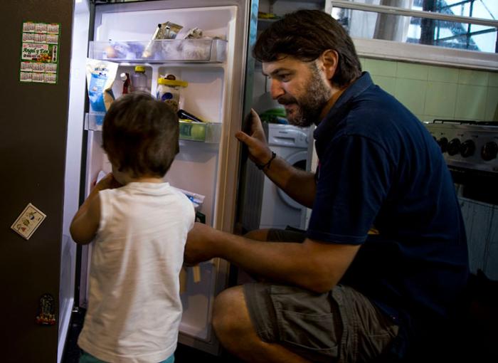 Padre con su hijo pequeño agarrando comida de la heladera