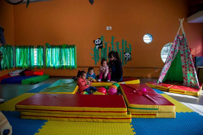 Niñas y educadora jugando en un salón de un centro Caif de nueva construcción