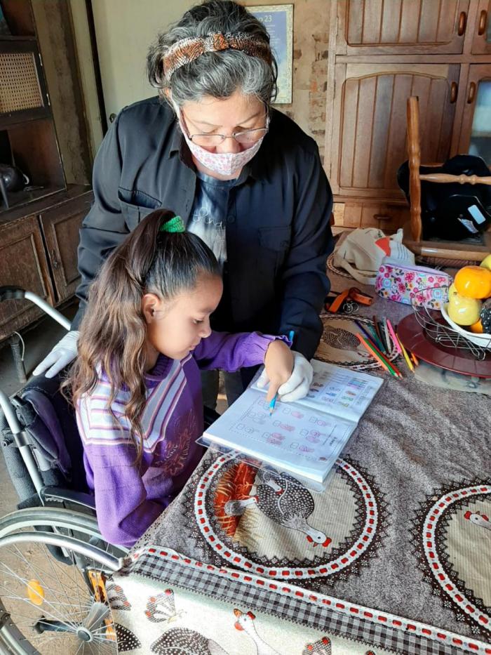 Elena, la asistente personal, ayuda a hacer las tareas escolares a Teresita, la niña a la que atiende.