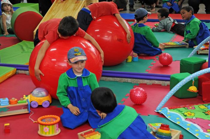 Niños y niñas jugan con pelotas gigantes en jardín de infantes 