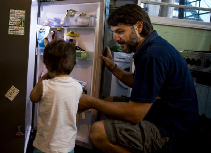 Nacho, padre que usó licencia parental de medio horario, abriendo la heladera junto a su hijo