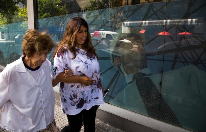 Asistente Personal Plan Piloto Asistente Personal junto a mujer mayor caminando por la calle frente a una vitrina
