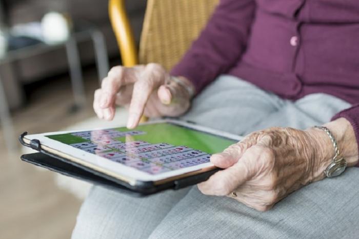 Manos de persona mayor jugando con su tablet