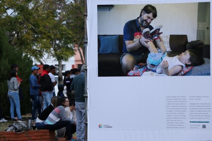 Instalación de fotos en Villa Constitución se ve la plaza y personas observando la muestra