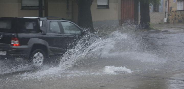 Camioneta en calle con agua, levantando una olita