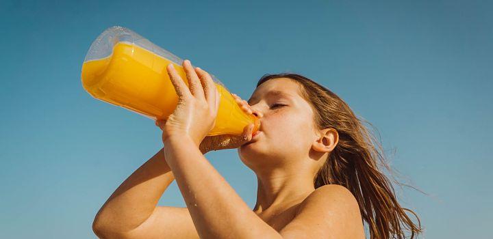 Recomendaciones frente a una ola de calor Niña bebiendo jugo de la botella