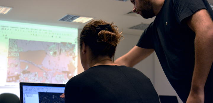 Capacitación en el uso de Datos Masivos para la eficiencia del Estado y la Integración Regional Mujera trabajando con mapas en una pc y hombre indicándole algo