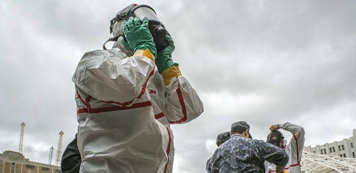 Se aprobó el Plan RAD para la atención de accidentes con materiales radioactivos Persona con máscara anti gas y traje anti radiación trabajando en simulacro en el puerto de Montevideo