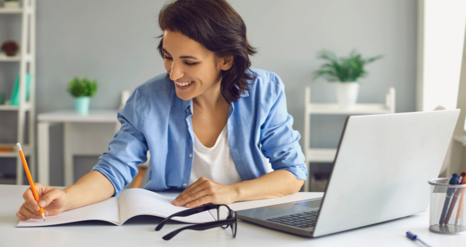 Mujer tomando nota en un curso virtual frente a su computadora Mujer tomando nota en un curso virtual frente a su computadora