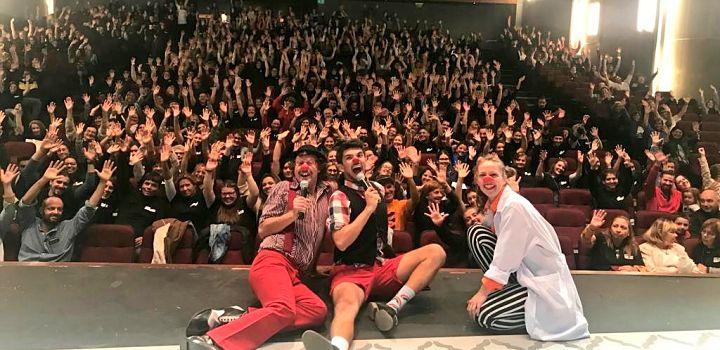 Foto desde el escenario donde se ven los payasos medicinales y el público llenando la sala.