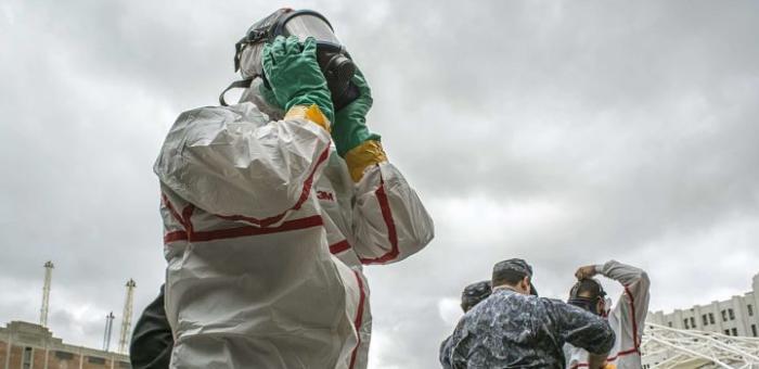 Persona con máscara anti gas y traje anti radiación trabajando en simulacro en el puerto de Montevideo