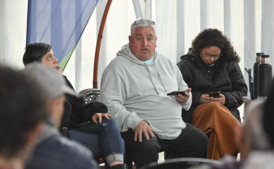 Vecino de Cerro Norte habla con un celular en la mano a otros vecinos, durante la asamblea para elaborar un plan de mejora ambiental
