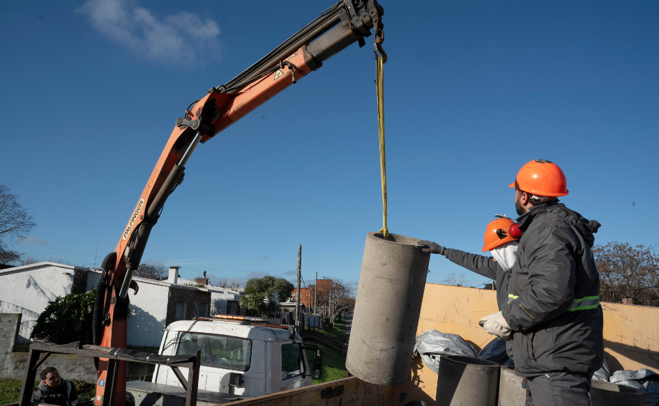 Funcionarios de la Intendencia de Canelones enganchan un caño desde la zorra de un camión en un guinche, durante las obras de acondicionamiento urbano en el barrio Corfrisa de Las Piedras, en el marco del programa Más Barrio