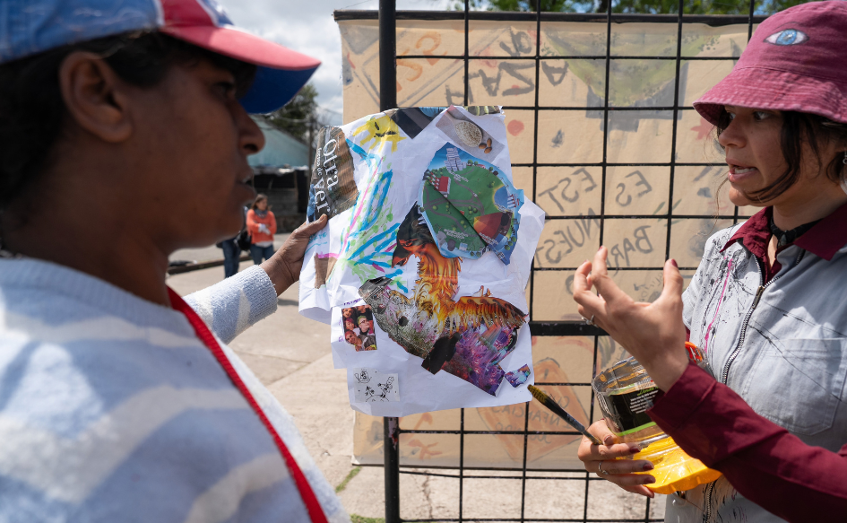 Dos mujeres hablan con un boceto y un tarro de pintura en la mano, en la plaza n°10 de Cerro Norte, durante la jornada comunitaria de Más Barrio para celebrar el comienzo de la primavera