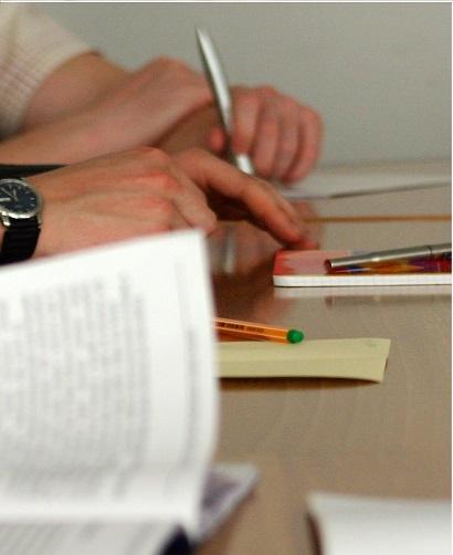 Manos de personas firmando un documento.