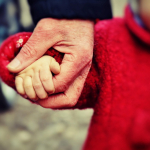Mano de adulto agarrando la mano de un niño