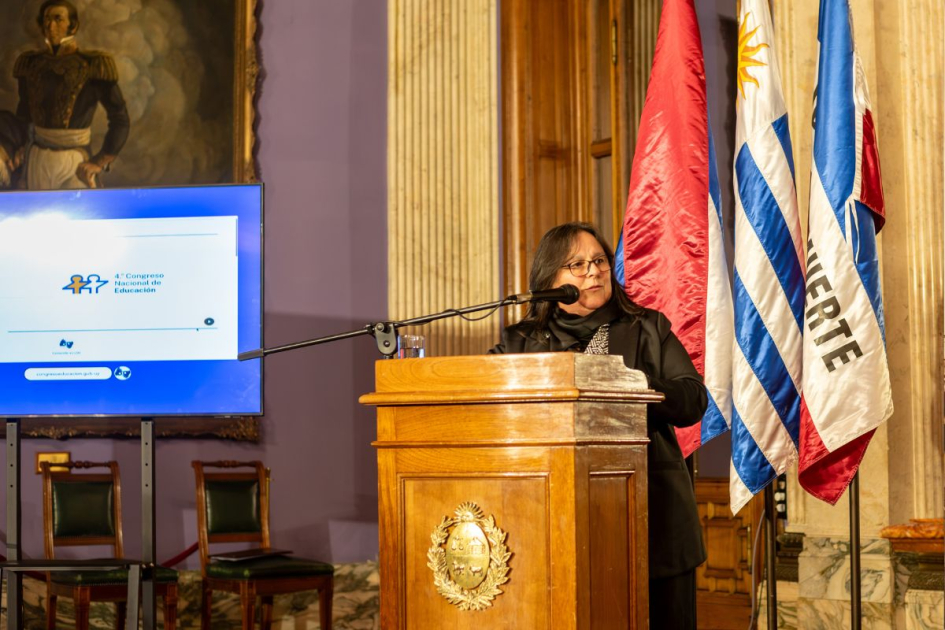 Persona en atril hablando con banderas patrias detrás.