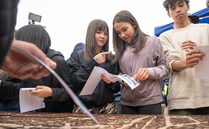 Tres adolescente integrantes de Ni Silencio Ni Tabú pegan stickers en una maqueta de Cerro Norte
