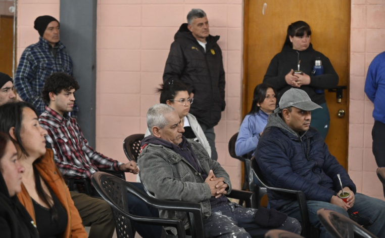 Vecinos de Cerro Norte, sentados y de pie, escuchan una presentación durante una asamblea vecinal