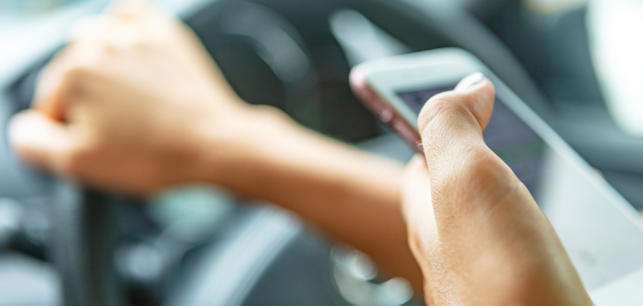 Imagen de una mano sosteniendo un teléfono celular mientras se conduce