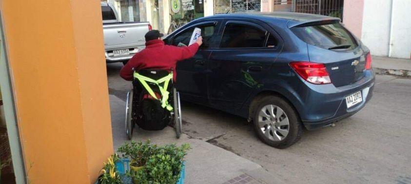 Usuario de silla de ruedas enfrentándose a una rampa obstaculizada por un auto Usuario de silla de ruedas enfrentándose a una rampa obstaculizada por un auto