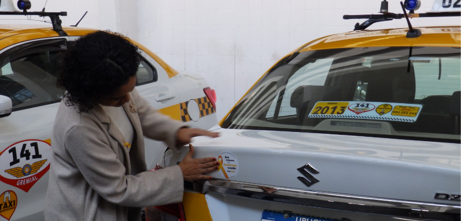 La Secretaria de Unasev en el momento en que coloca el sticker número 1000 en los taxis de Montevide