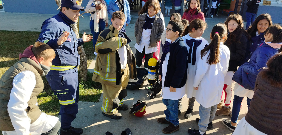 Oficial del cuerpo de Bomberos instruyendo a escolares sobre la vestimenta que utilizan Oficial del cuerpo de Bomberos instruyendo a escolares sobre la vestimenta que utilizan
