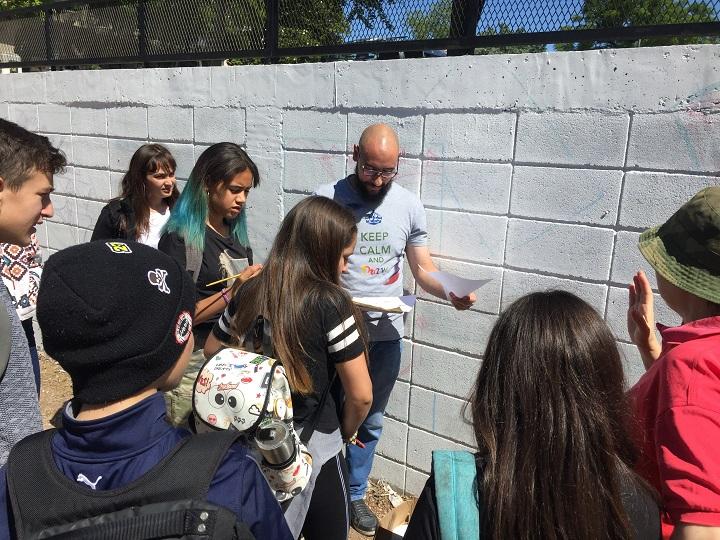 Estudiantes junto a docente realizando los primeros trazos sobre el muro