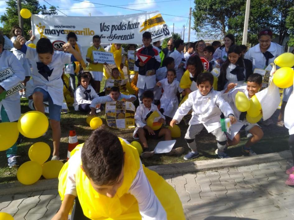 Escolares de Artigas en actividad Mayo Amarillo en espacio abierto con pancarta alusiva