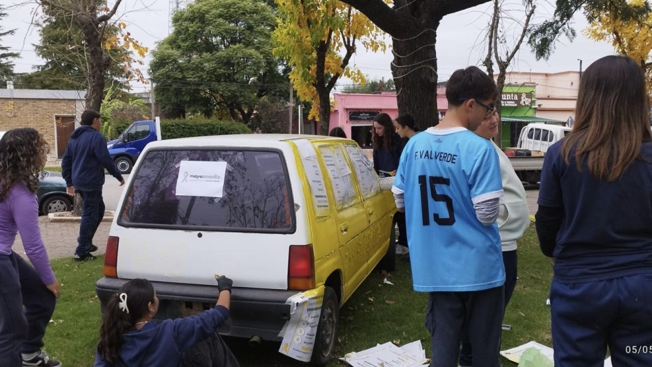 Adolescentes pintan un auto de amarillo en el marco de las acciones de concientización