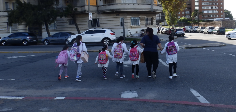 Madre cruzando de la mano con escolares