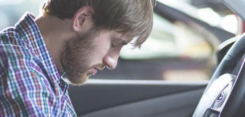 Hombre al volante con la cabeza hacia abajo 