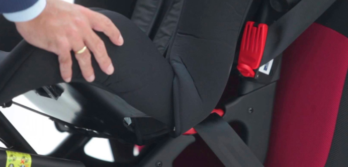 Una mano maniobra en actitud de instalar una silla para niño en el auto