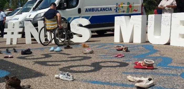 Siniestrado en silla de ruedas frente a cartel Nos Mueve la Vida