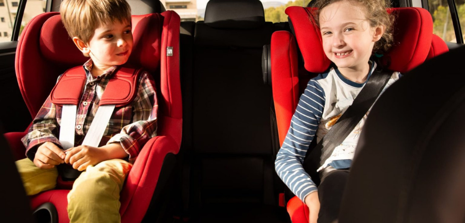 Imagen de dos niños ubicados en el asiento trasero de un vehículo en su correspondiente SRI cada uno