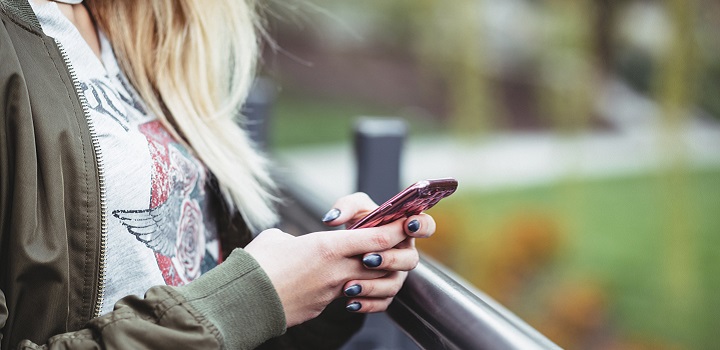 Encuesta para jóvenes Foto de perfil de una adolescente con un teléfono celular en la mano