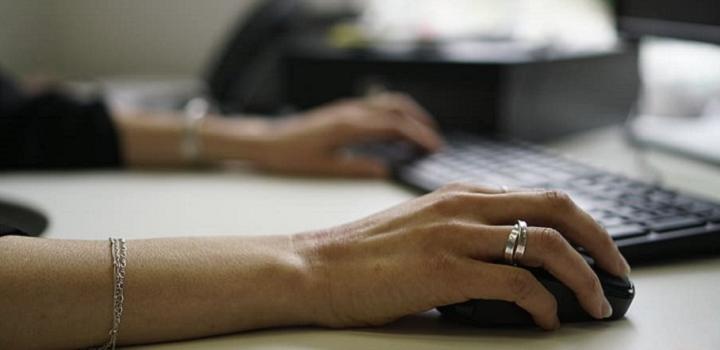 Constitución de domicilio electrónico manos de mujer junto a un teclado y una pantalla de computadora