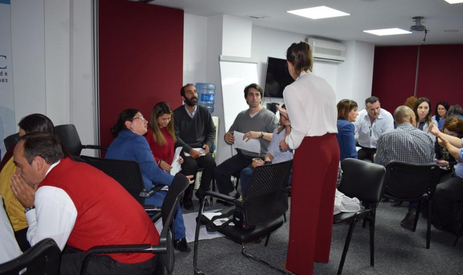 Foto de funcionarios de URSEC y Mercedes Aramendia interactuando durante la actividad práctica del taller