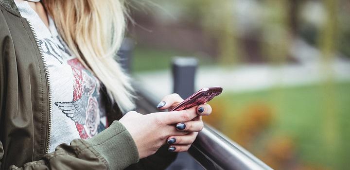 Foto de perfil de una adolescente con un teléfono celular en la mano