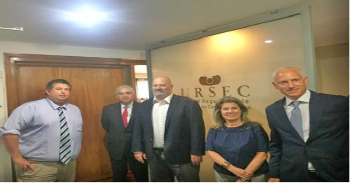 Presidente y directores de Ursec parados junto a los visitantes detrás de un vidrio que dice Ursec