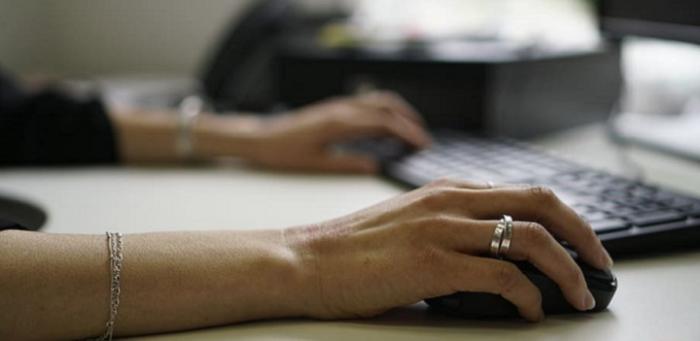 manos de mujer junto a un teclado y una pantalla de computadora